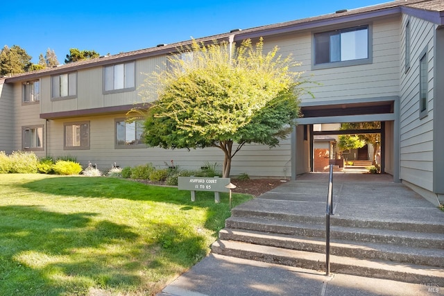 townhome / multi-family property featuring a carport, driveway, and a front yard