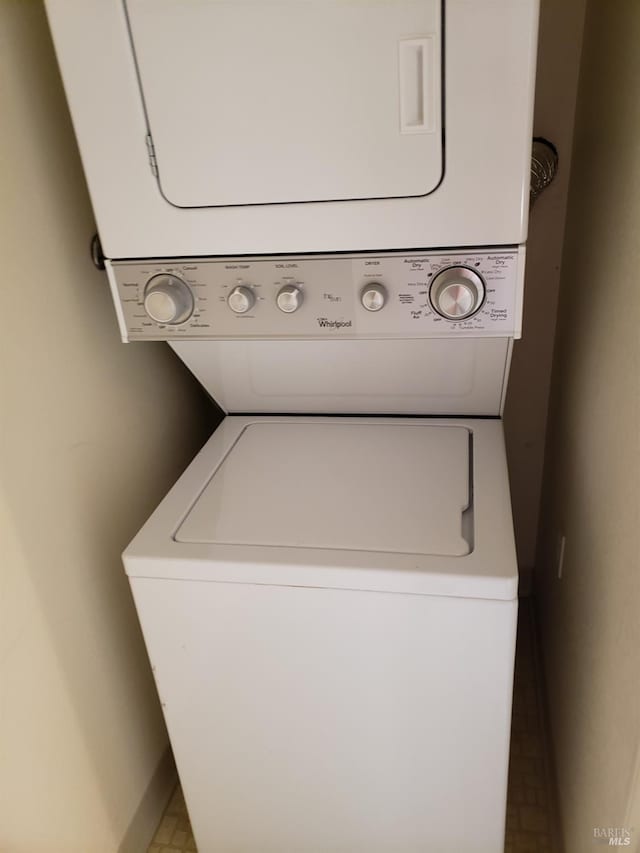 laundry area featuring laundry area, baseboards, and stacked washing maching and dryer