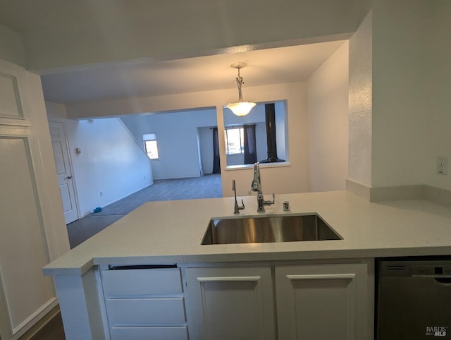 kitchen with a sink, decorative light fixtures, open floor plan, light countertops, and dishwashing machine