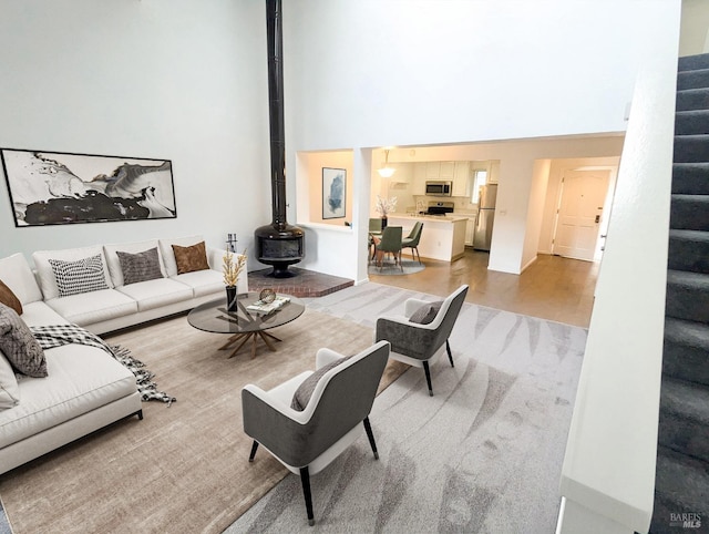 living room featuring a wood stove and a towering ceiling