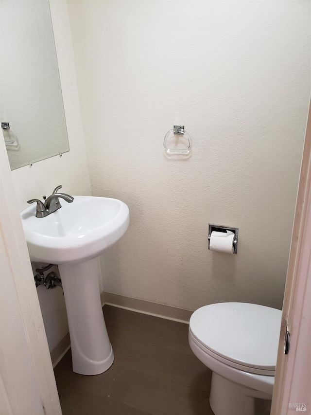 half bathroom featuring toilet and baseboards