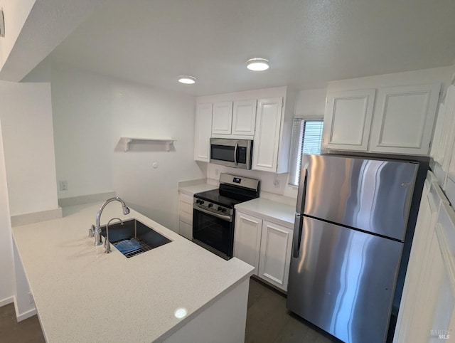 kitchen featuring a sink, stainless steel appliances, a peninsula, white cabinets, and light countertops