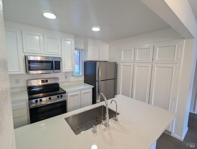 kitchen featuring light stone countertops, appliances with stainless steel finishes, white cabinetry, and a sink