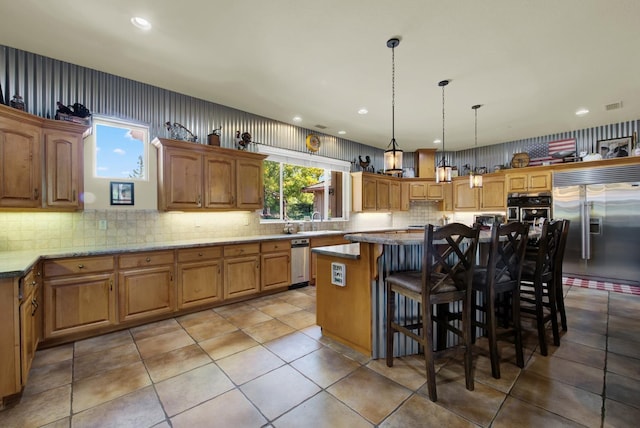 kitchen featuring built in fridge, a kitchen island, decorative light fixtures, a breakfast bar area, and light stone counters