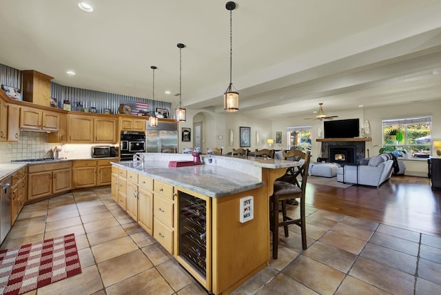 kitchen with a large island, pendant lighting, a breakfast bar, appliances with stainless steel finishes, and wine cooler