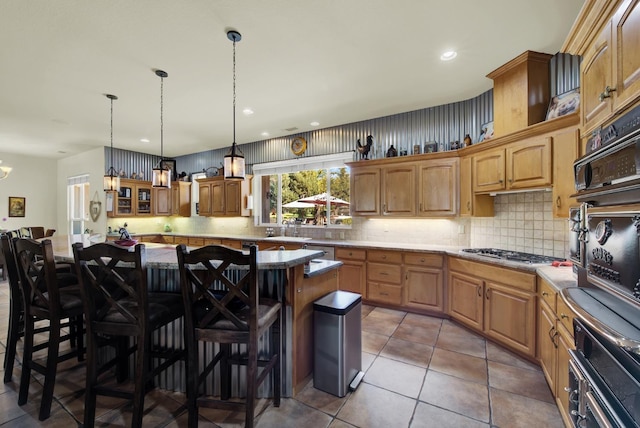 kitchen featuring appliances with stainless steel finishes, a kitchen breakfast bar, a center island, decorative backsplash, and tile patterned floors