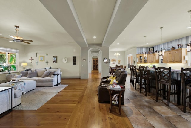 living room featuring ceiling fan with notable chandelier and dark hardwood / wood-style flooring