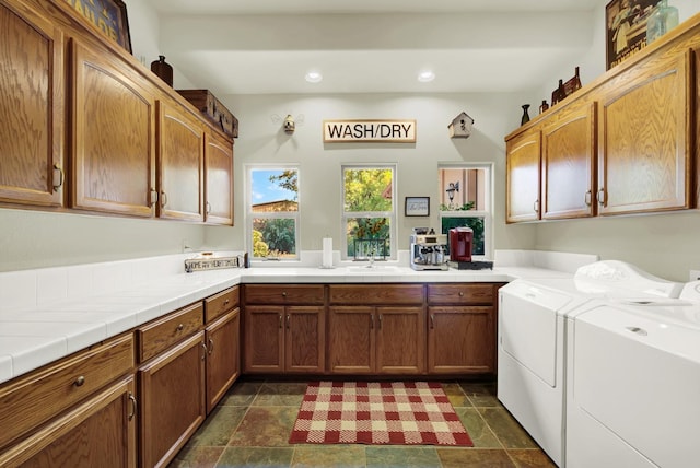 washroom featuring sink, washing machine and dryer, and cabinets