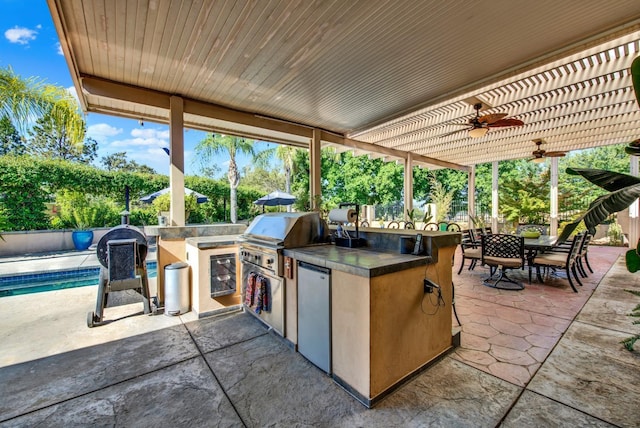 view of patio featuring ceiling fan, area for grilling, a pergola, and exterior kitchen