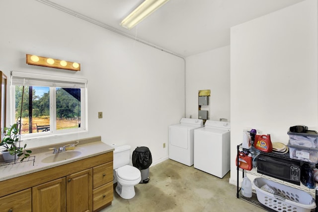 bathroom featuring washing machine and dryer, sink, concrete floors, and toilet