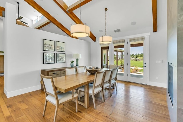 dining room with vaulted ceiling with beams and light hardwood / wood-style floors