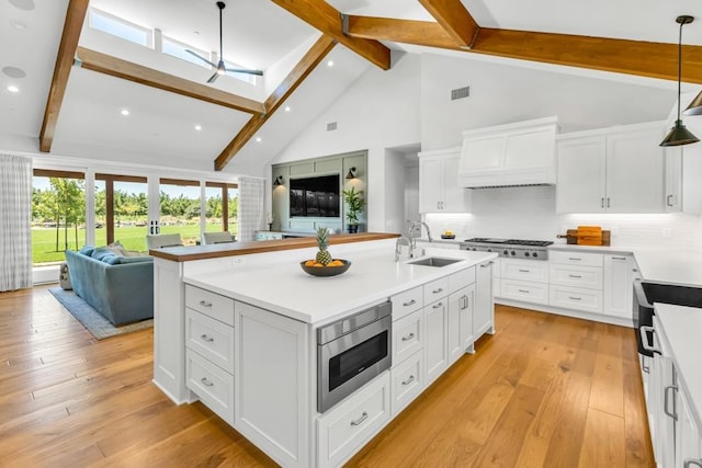 kitchen featuring sink, white cabinets, hanging light fixtures, stainless steel appliances, and custom range hood