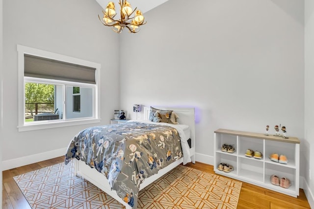 bedroom featuring lofted ceiling, wood-type flooring, and a chandelier