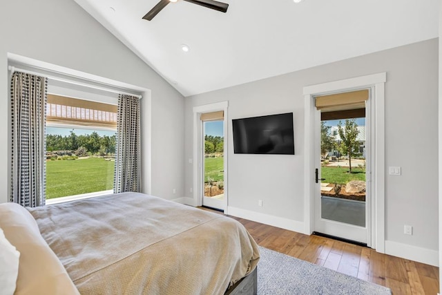 bedroom with hardwood / wood-style floors, vaulted ceiling, multiple windows, and access to outside