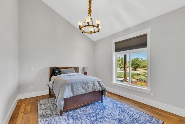 bedroom with hardwood / wood-style flooring, a chandelier, and vaulted ceiling