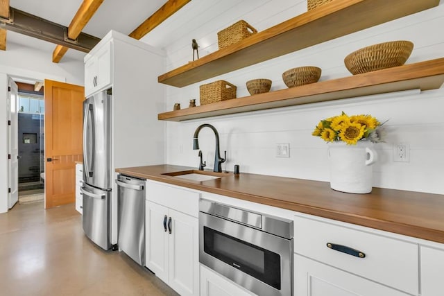 kitchen with stainless steel appliances, butcher block counters, sink, and white cabinets