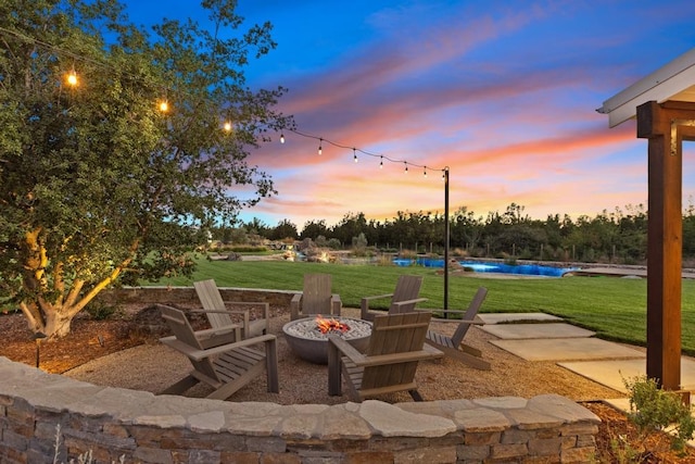 patio terrace at dusk featuring a lawn and an outdoor fire pit