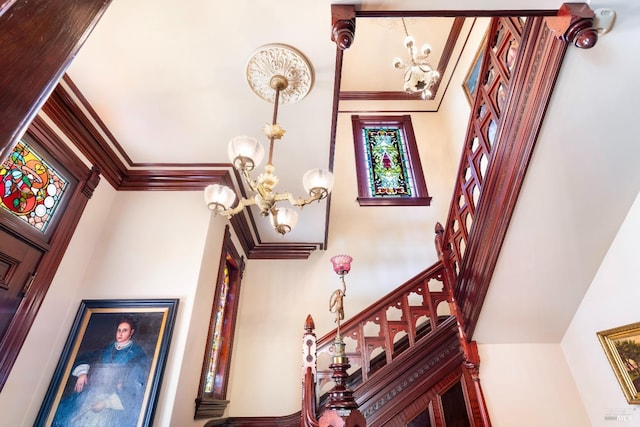 staircase featuring a high ceiling, ornamental molding, and a notable chandelier