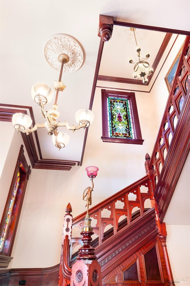 staircase with a towering ceiling, crown molding, and a chandelier