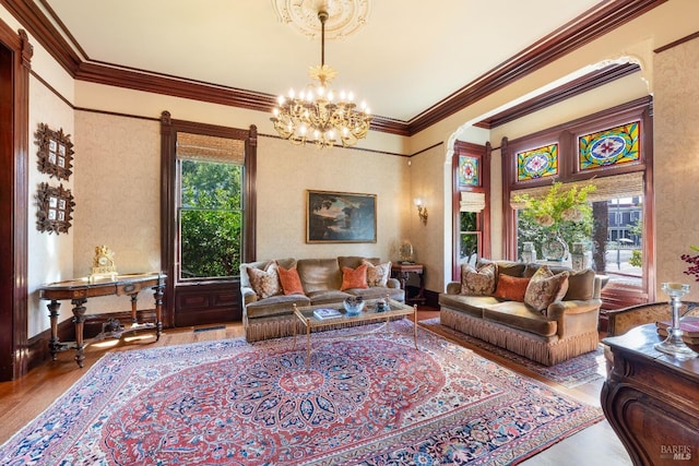 living room featuring wood-type flooring, ornamental molding, a chandelier, and plenty of natural light