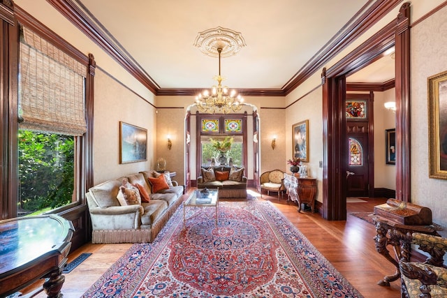 living room with a notable chandelier, light wood-type flooring, and crown molding