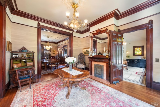 sitting room with an inviting chandelier, hardwood / wood-style flooring, and crown molding