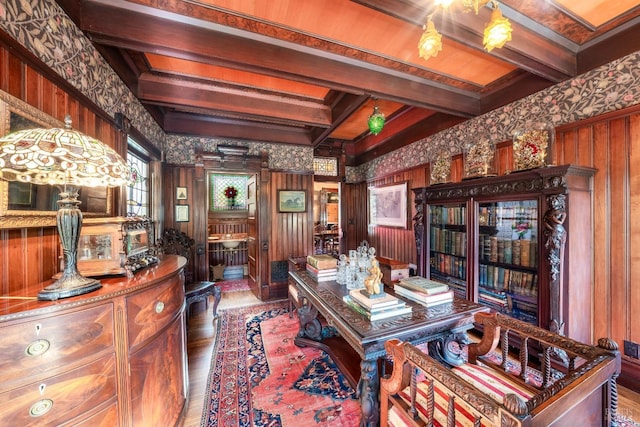 home office with wooden walls, beam ceiling, and hardwood / wood-style floors