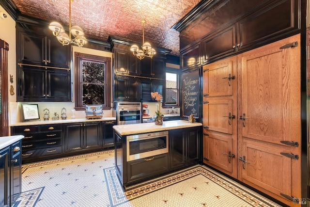 kitchen featuring pendant lighting, stainless steel appliances, a notable chandelier, and ornamental molding