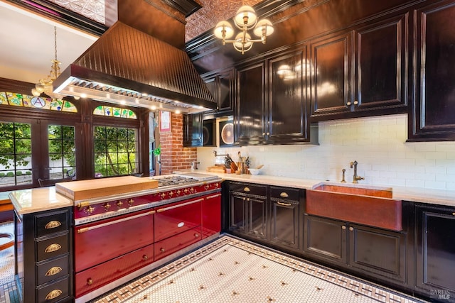 kitchen featuring sink, a notable chandelier, hanging light fixtures, stainless steel cooktop, and premium range hood