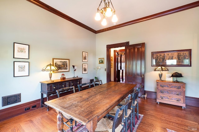 dining area featuring ornamental molding, a chandelier, and dark hardwood / wood-style flooring