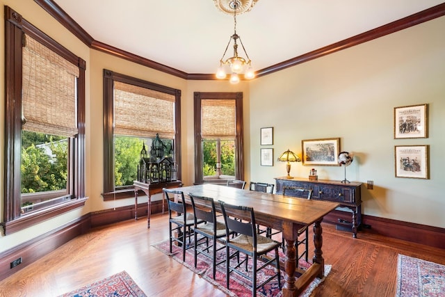 dining space with ornamental molding, a notable chandelier, and hardwood / wood-style flooring