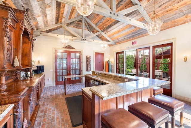 kitchen with hanging light fixtures, a center island, french doors, and light stone counters