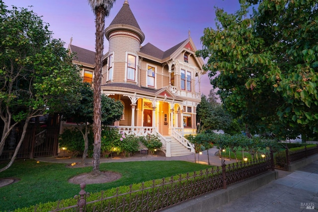 victorian-style house with a lawn and covered porch