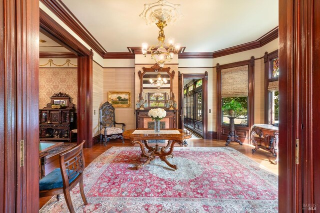 sitting room featuring hardwood / wood-style floors, ornamental molding, and an inviting chandelier