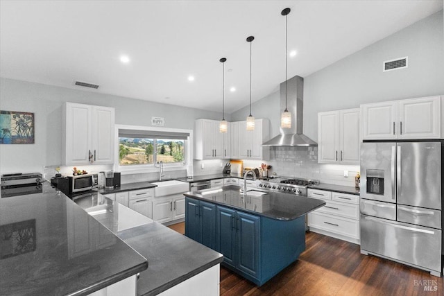 kitchen with stainless steel appliances, a sink, visible vents, wall chimney exhaust hood, and an island with sink