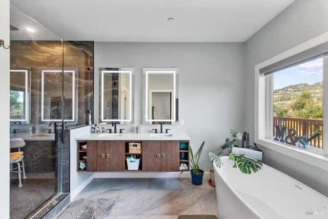 full bathroom featuring double vanity, a freestanding tub, a shower stall, and a sink