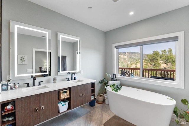 full bath featuring double vanity, a freestanding tub, and a sink