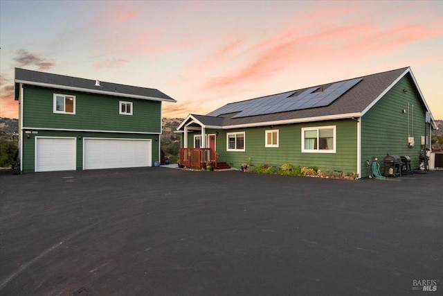 view of front facade with a garage, driveway, and solar panels