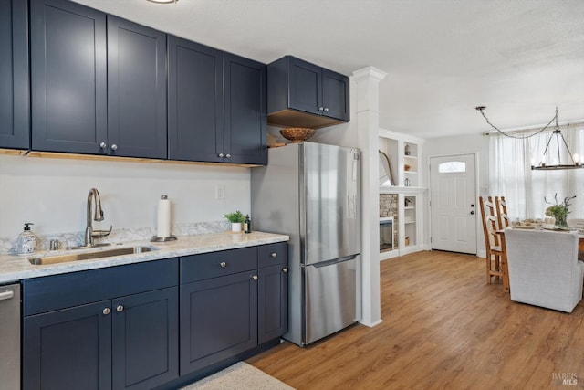 kitchen featuring appliances with stainless steel finishes, light wood-type flooring, built in shelves, sink, and a chandelier