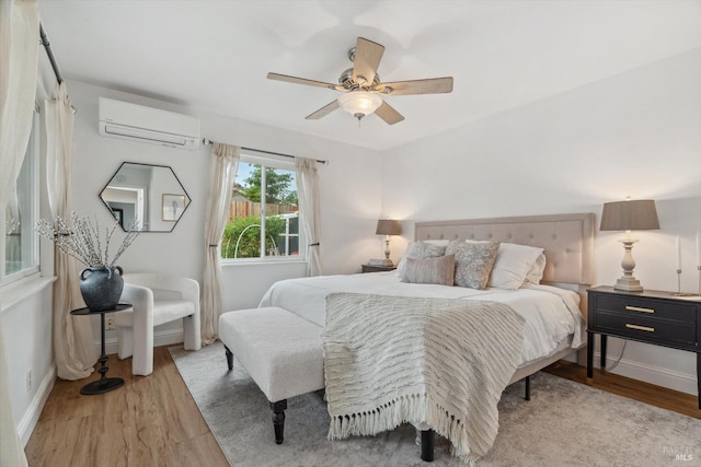 bedroom featuring ceiling fan, light hardwood / wood-style floors, and a wall unit AC