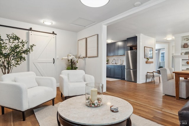 living room featuring a barn door, hardwood / wood-style floors, and sink