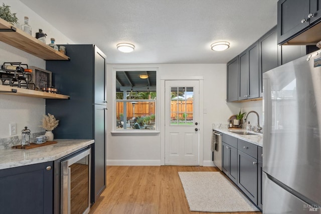 kitchen featuring sink, wine cooler, a textured ceiling, light hardwood / wood-style floors, and stainless steel appliances