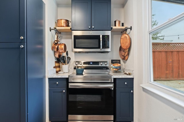 kitchen featuring light stone countertops, a wealth of natural light, stainless steel appliances, and blue cabinets