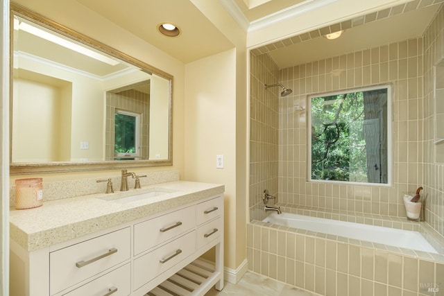 bathroom with crown molding, vanity, and tiled shower / bath