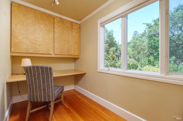 home office featuring crown molding, built in desk, and hardwood / wood-style flooring