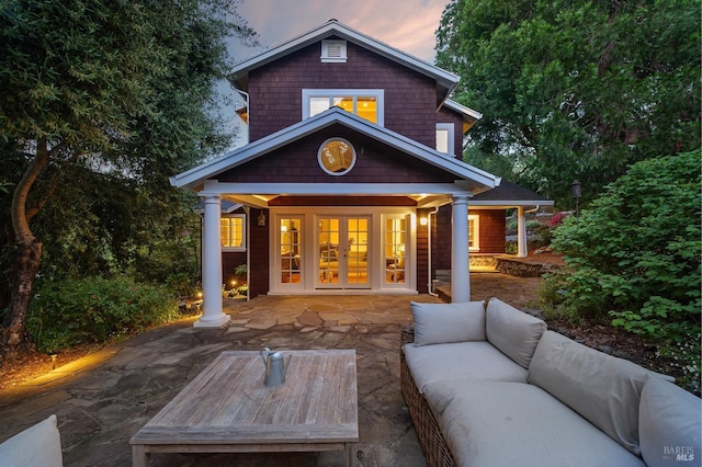 back house at dusk with a patio, outdoor lounge area, and french doors