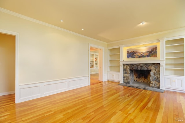 unfurnished living room featuring a stone fireplace, light hardwood / wood-style flooring, and ornamental molding