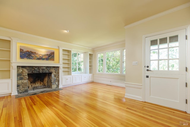 unfurnished living room featuring crown molding, a fireplace, built in features, and light wood-type flooring