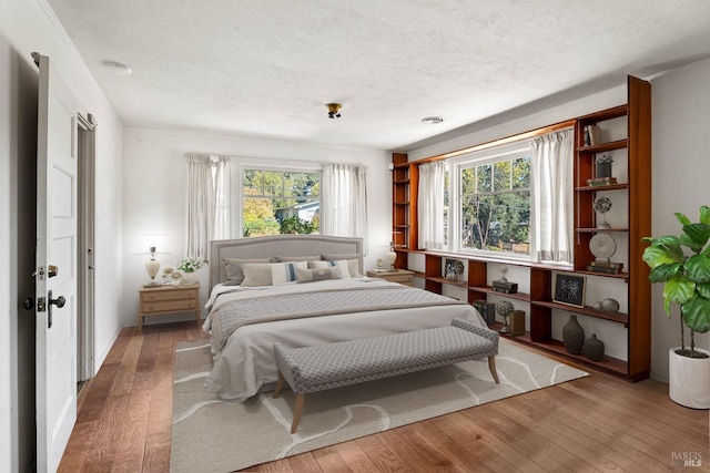 bedroom with wood-type flooring, a textured ceiling, and baseboards