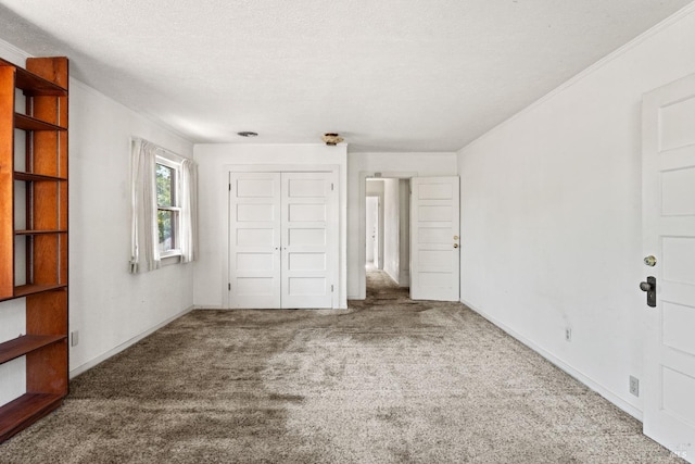 unfurnished bedroom with ornamental molding, a closet, a textured ceiling, and carpet flooring